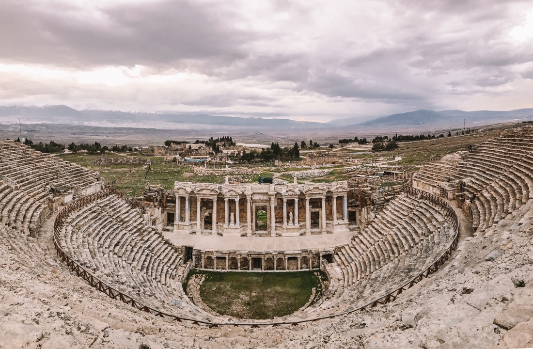Ancient amphitheater ruins with a vast landscape in the background.