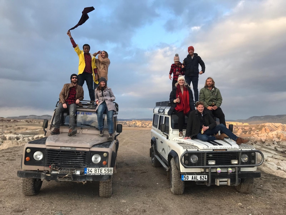 A group of people posing on top of two off-road vehicles in a rocky area.