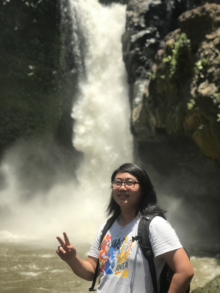 A woman standing in front of a waterfall.