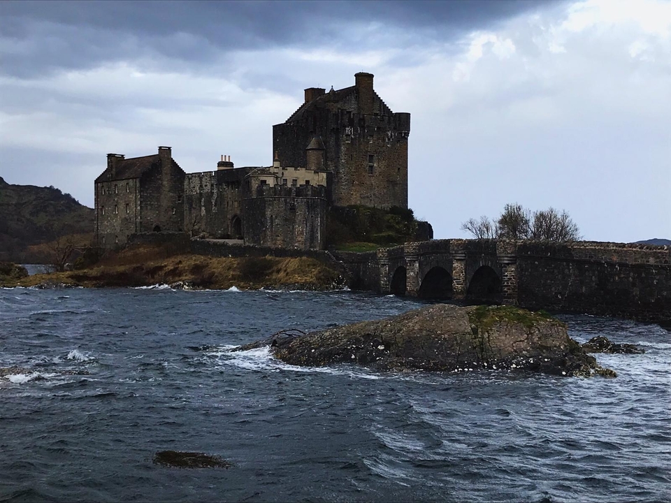 Eilean Donan Castle with stone bridge and turbulent waters.