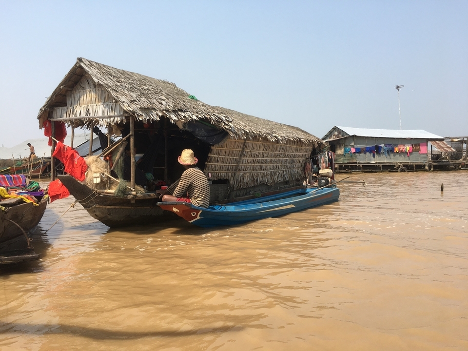 Bateau traditionnel cambodgien sur une rivière boueuse.