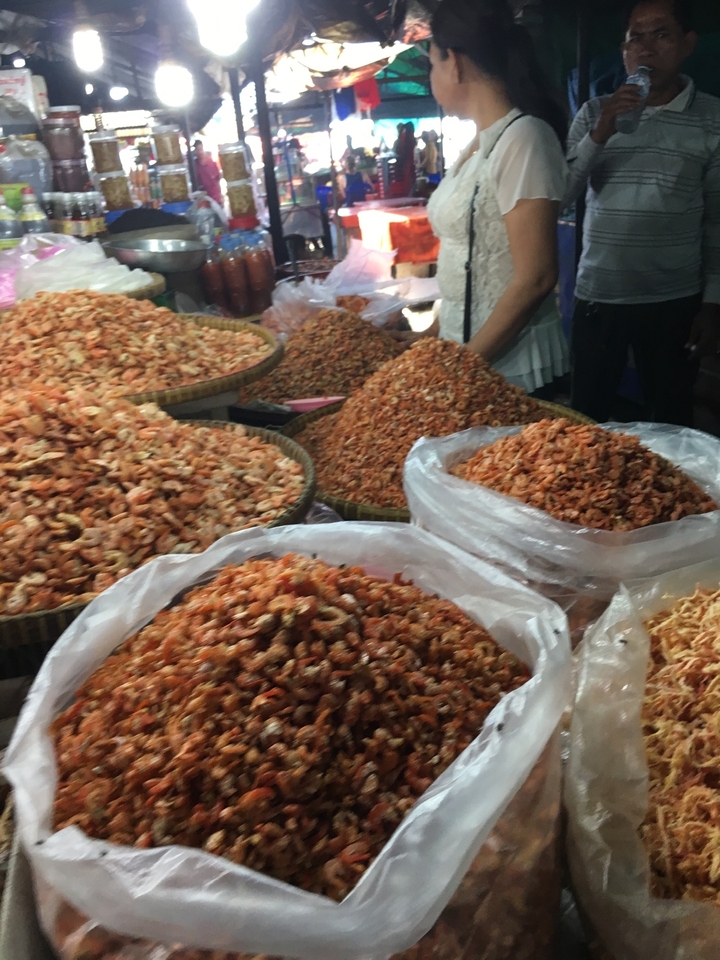Crevettes séchées empilées dans des sacs et des paniers sur un marché.