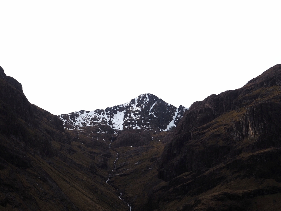Mountain peak with snow, clear sky above.