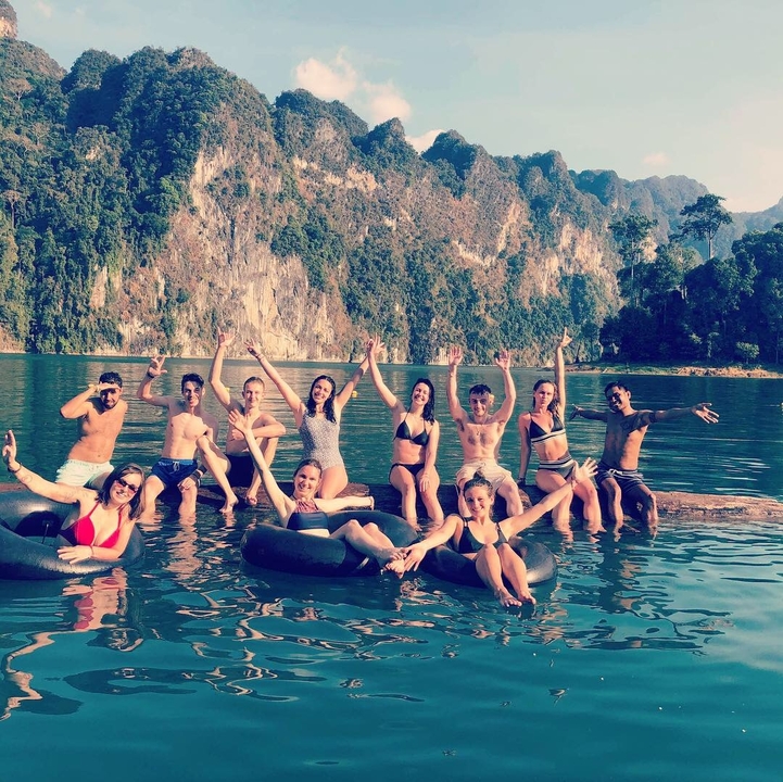 Group enjoying swimming and floating in a lake with scenic cliffs.
