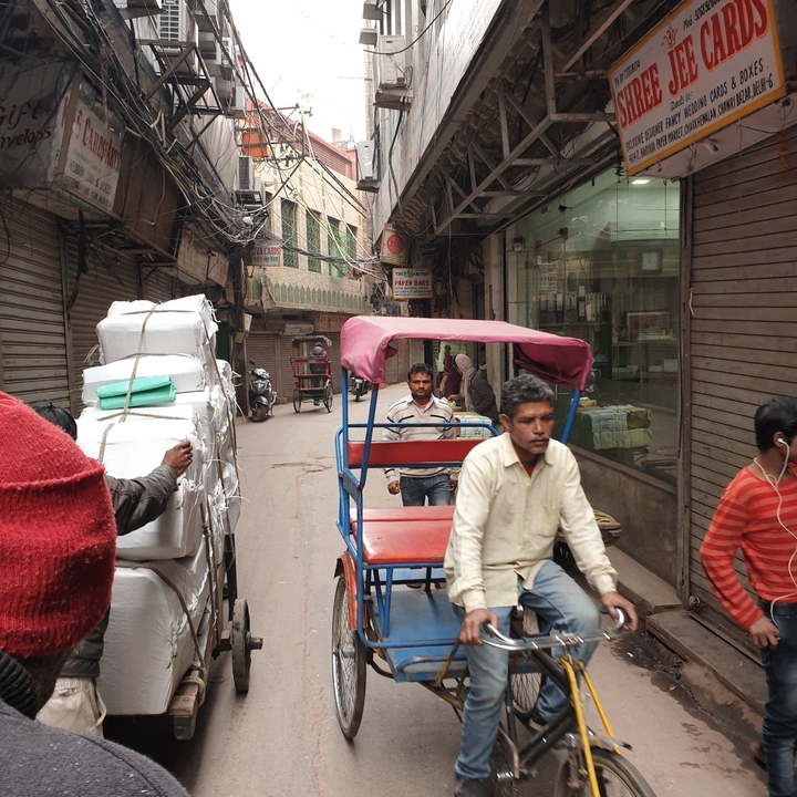 Bustling street with rickshaw and people in New Delhi