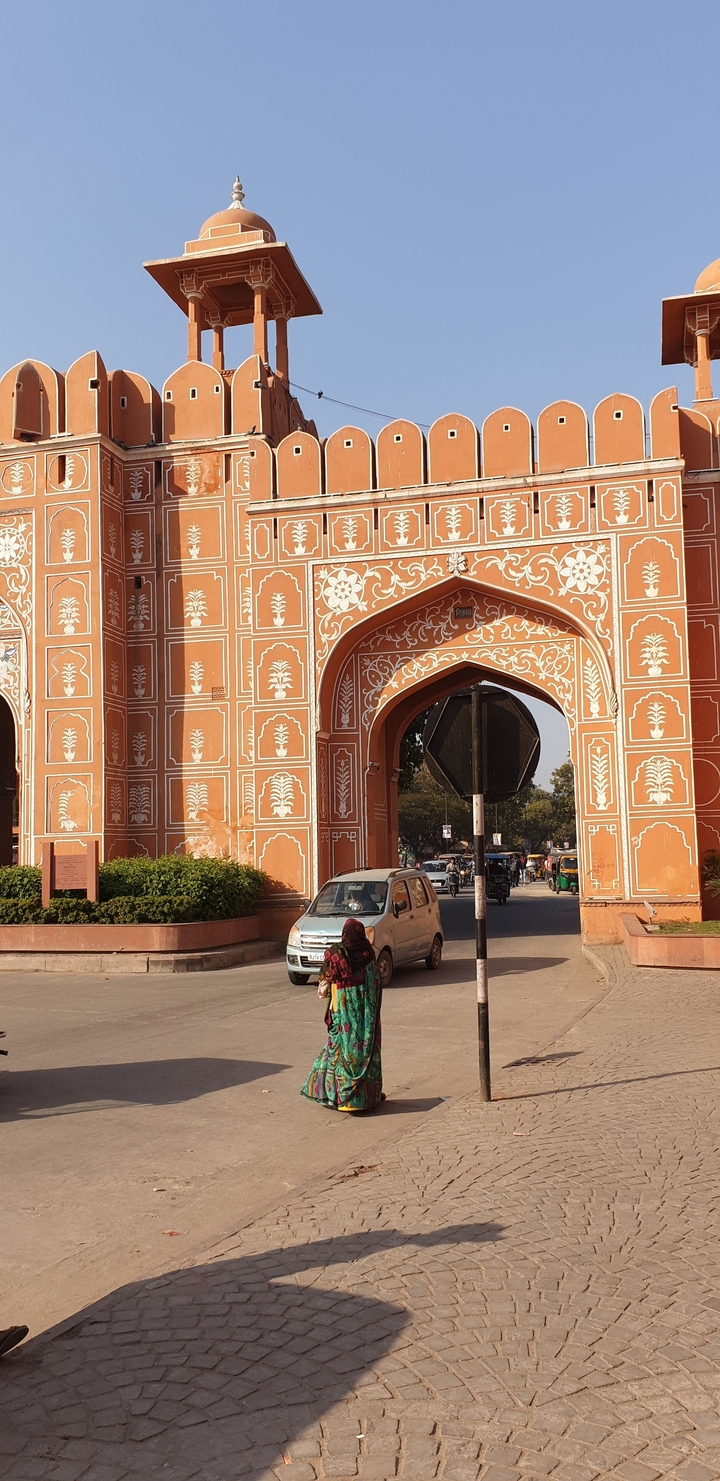 Ornate architectural structure with arches and detailed designs, and a parked car in the foreground.