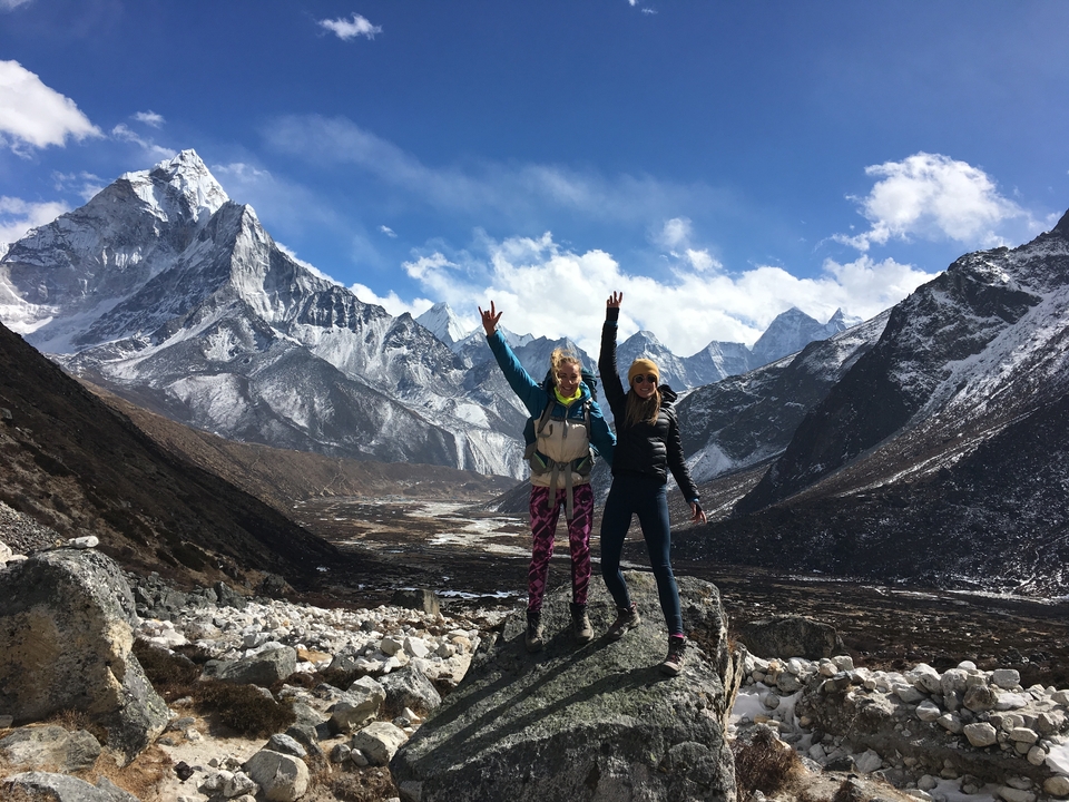Deux personnes posant avec enthousiasme devant de majestueuses montagnes enneigées.
