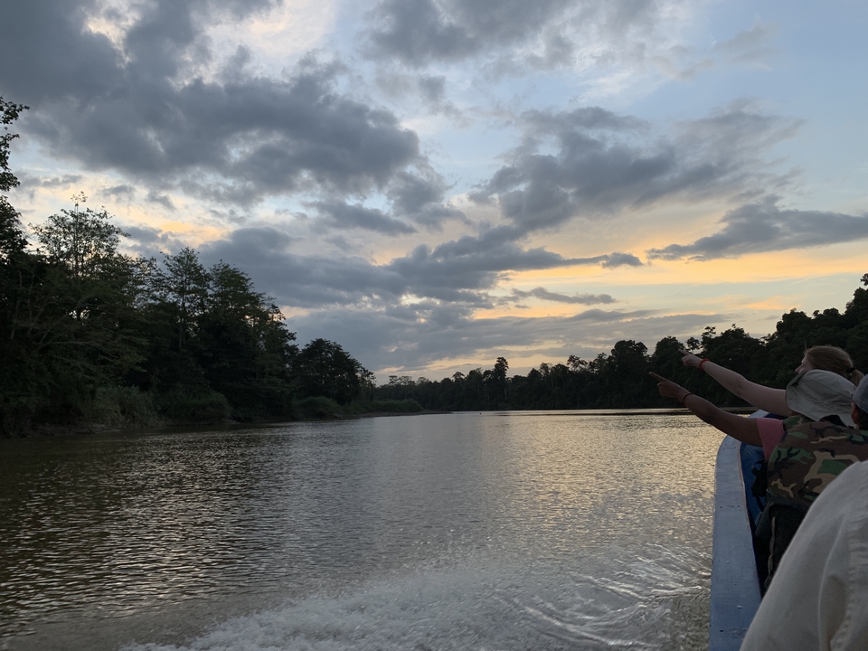 Vue pittoresque sur la rivière avec des gens pointant vers l'eau pendant le coucher du soleil.