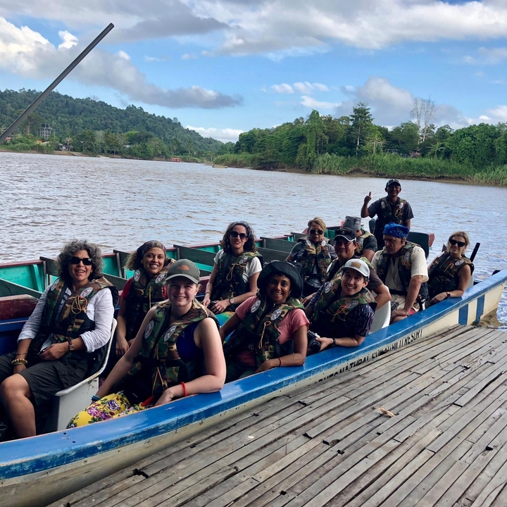 Groupe de personnes en gilets de sauvetage assises dans un bateau au bord de la rivière.