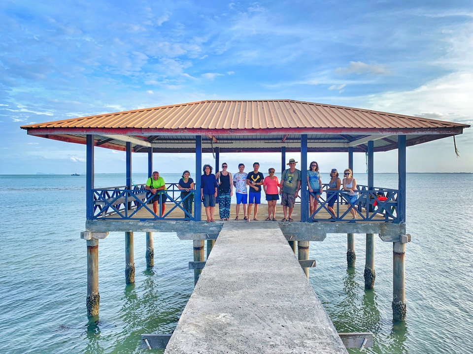 Groupe de personnes qui posent sur une jetée au-dessus de l'océan.