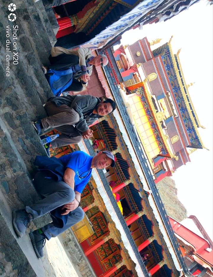 Trois personnes assises sur les marches d'un temple décoré.