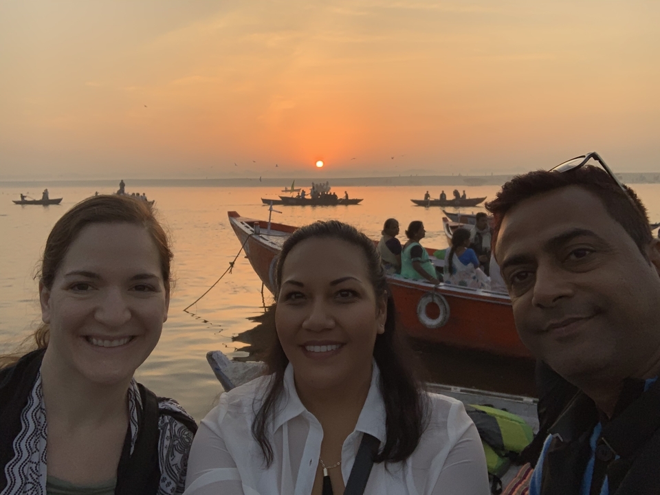 Groupe de personnes sur un bateau au coucher du soleil avec d'autres bateaux en arrière-plan.