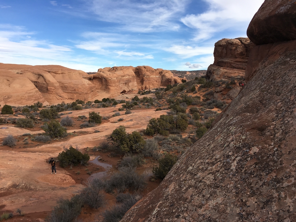Randonneur dans un paysage désertique avec des formations rocheuses rouges.
