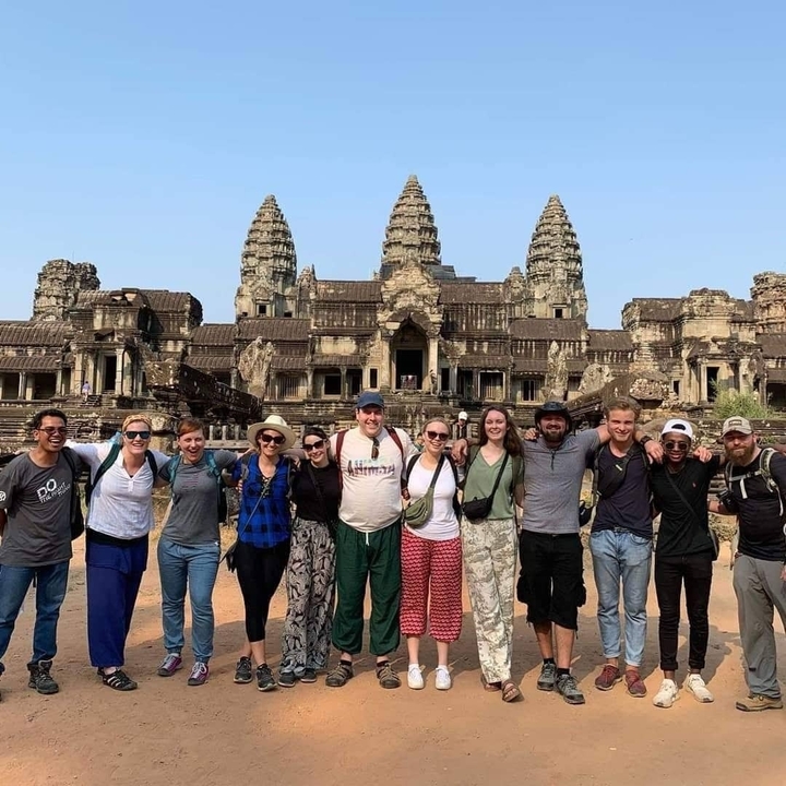 Group of tourists posing in front of Angkor Wat.