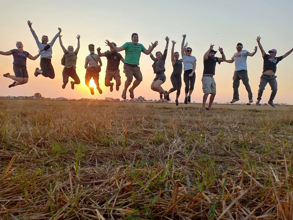 Groupe de personnes sautant dans les airs au coucher du soleil.