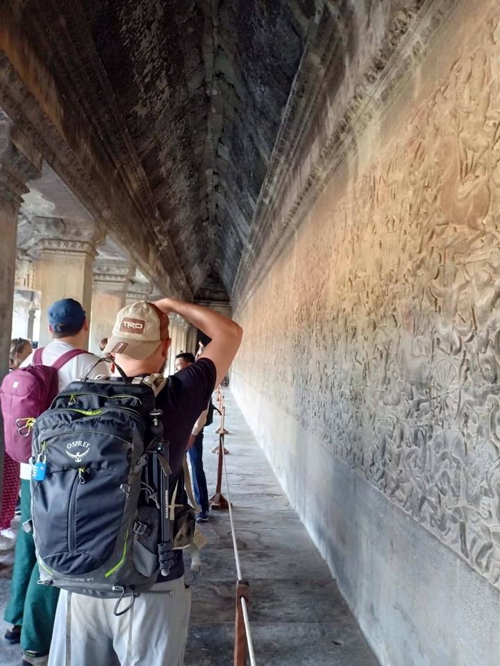 Des touristes observant des sculptures murales complexes.