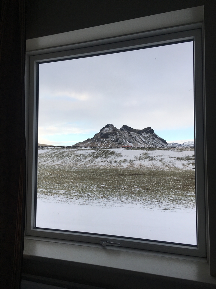 View of a mountain through a window in a snow-dusted landscape.