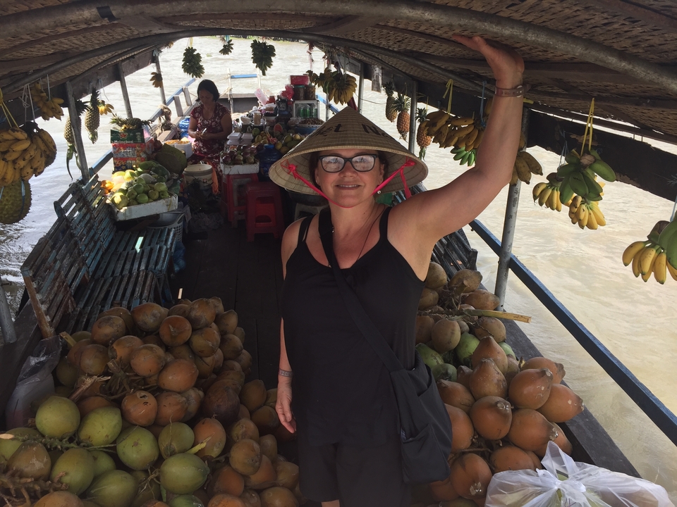 Femme debout sur un bateau de marché flottant avec des fruits.