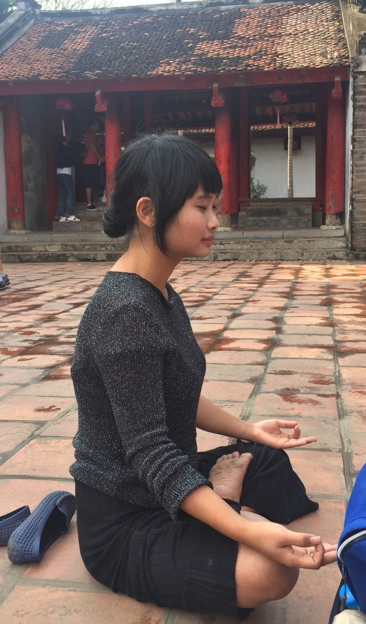 Profil d'une femme assise sur un sol carrelé.
