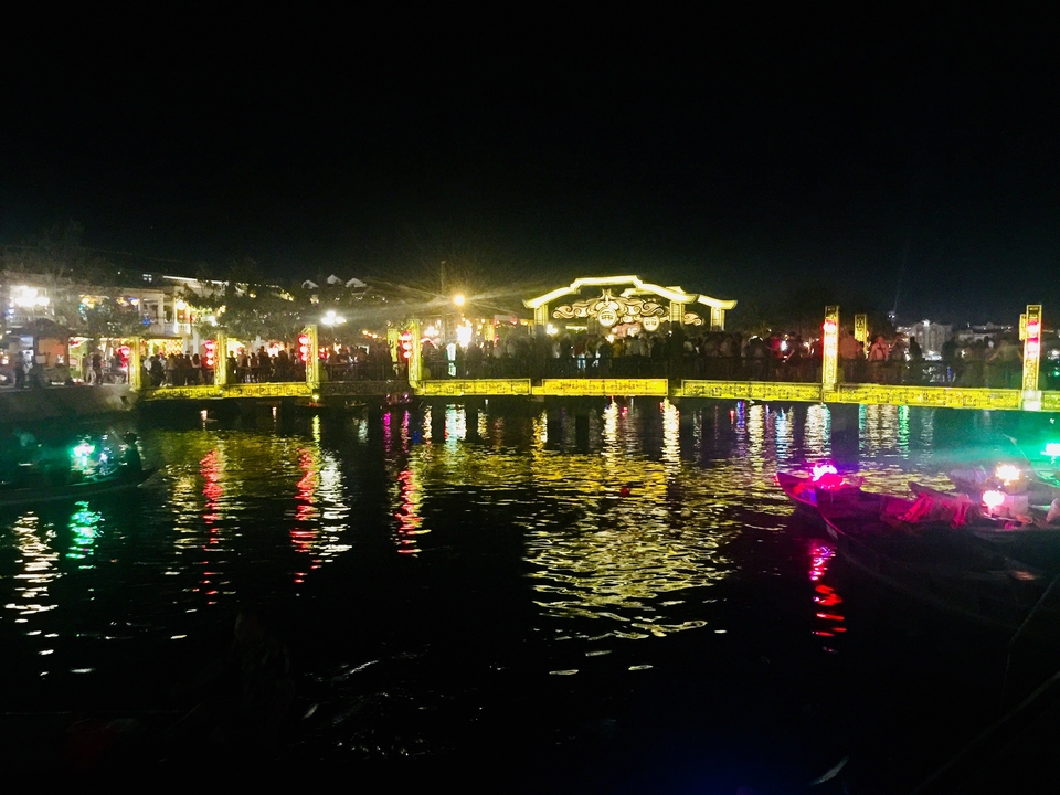 Un pont éclairé la nuit avec des reflets sur l'eau.