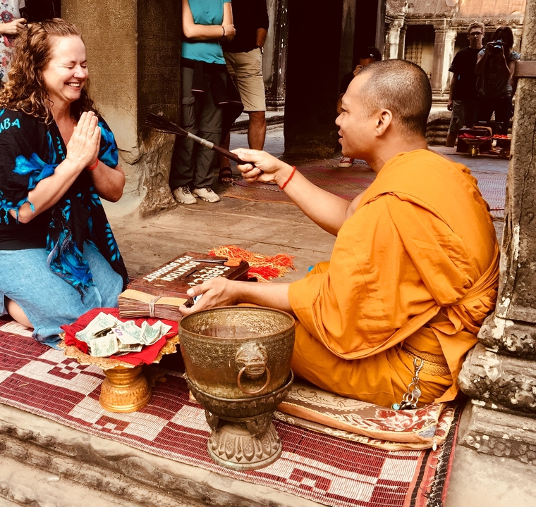 Moine bénissant une personne avec des offrandes devant.
