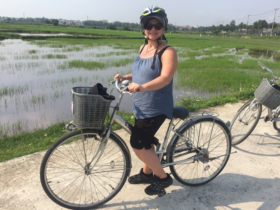 Une personne portant un casque qui fait du vélo près d'un champ de riz.