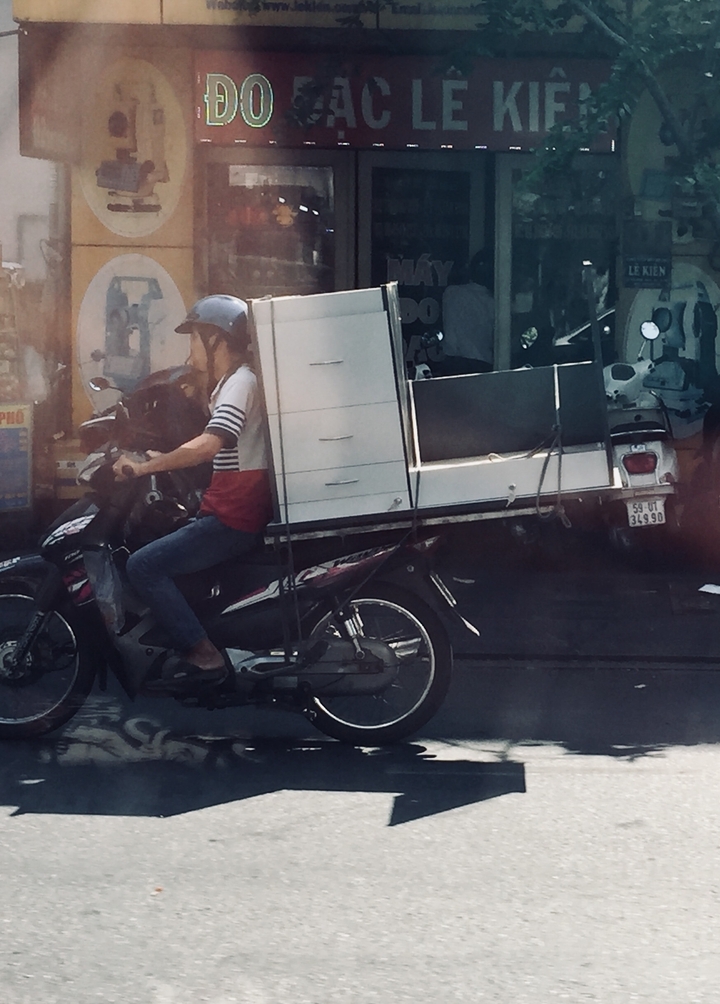 Personne sur une moto transportant une armoire.