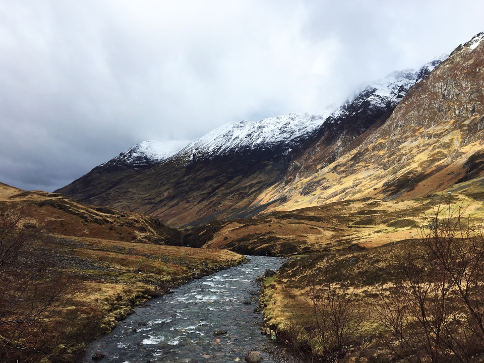 A scenic view of a river and snow-capped mountains.