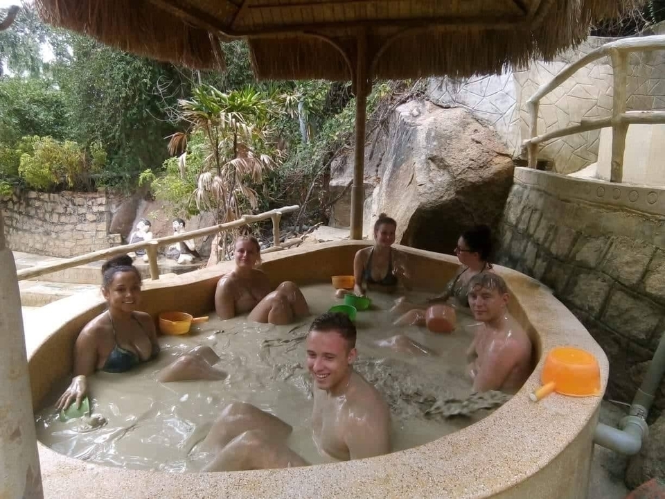 People enjoying a mud bath in an outdoor setting.
