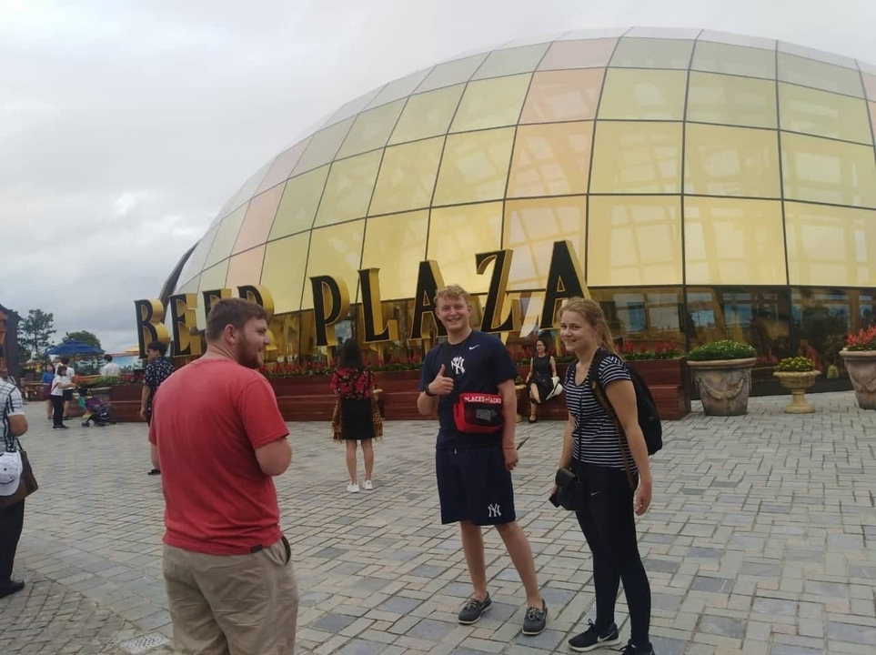 People posing in front of a Beer Plaza building.