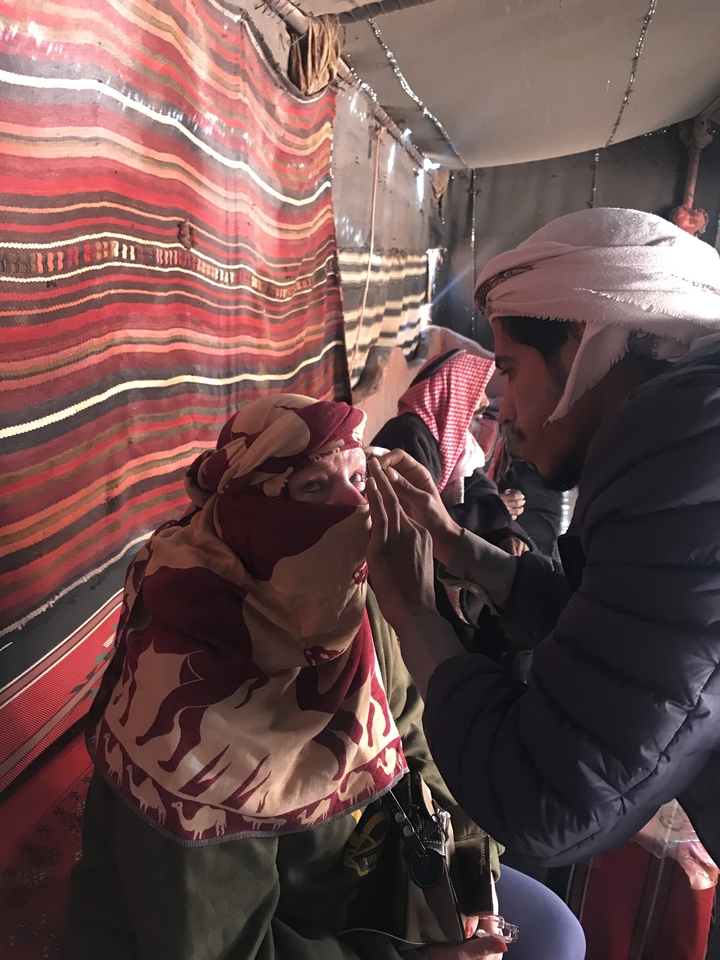 Two people dressed in traditional attire inside a tent.