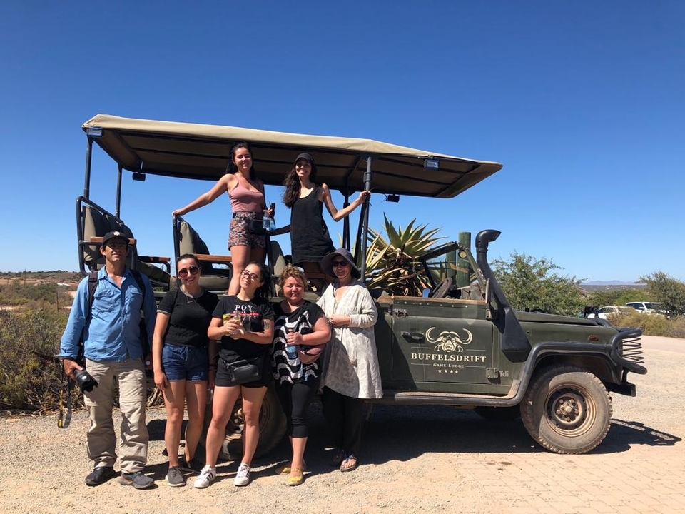 Group of people posing with a safari vehicle.