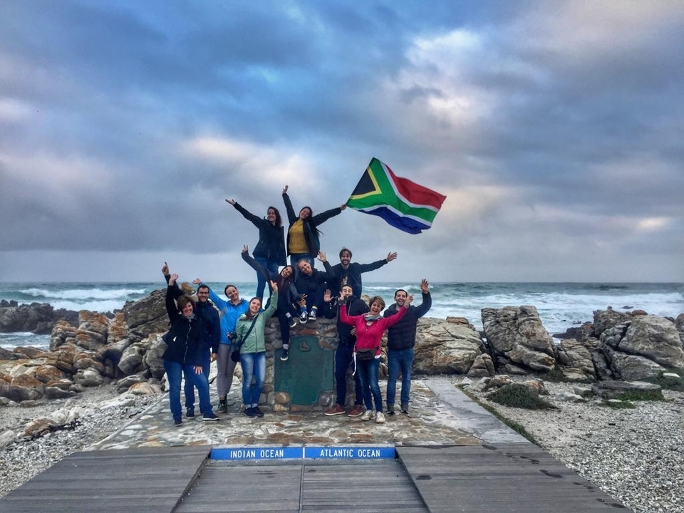 Groupe de personnes célébrant sur une côte rocheuse avec un drapeau.