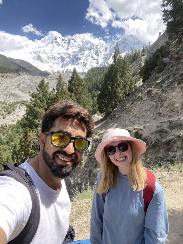 Two people hiking with a snowy mountain in the background.