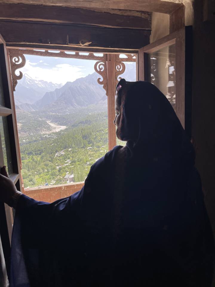 Silhouette of a person looking out over mountains from a window.