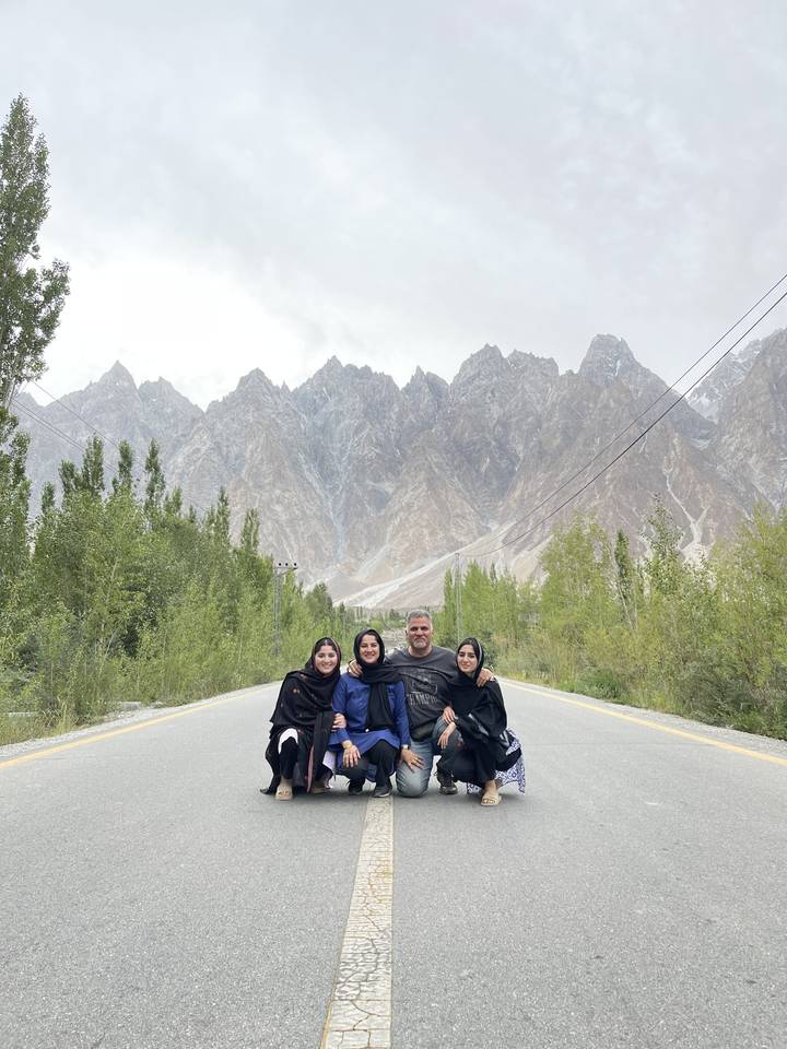 Group of people posing on a road with mountains in the background.