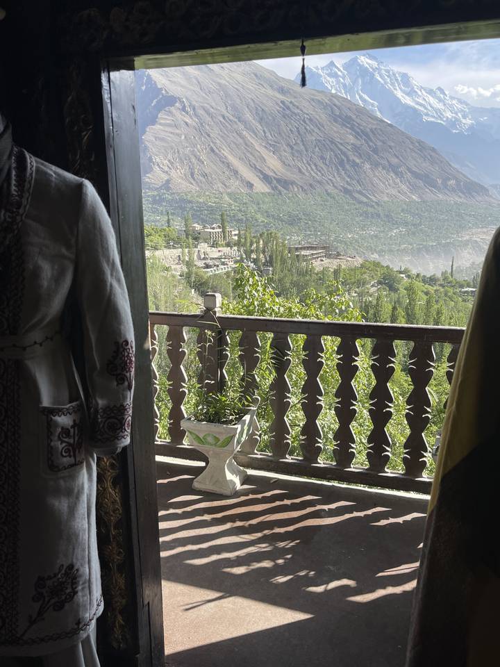 View of mountains from a balcony with intricate wooden railing.