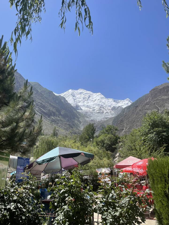 Snow-covered mountain peaks against a clear blue sky, umbrellas in view.