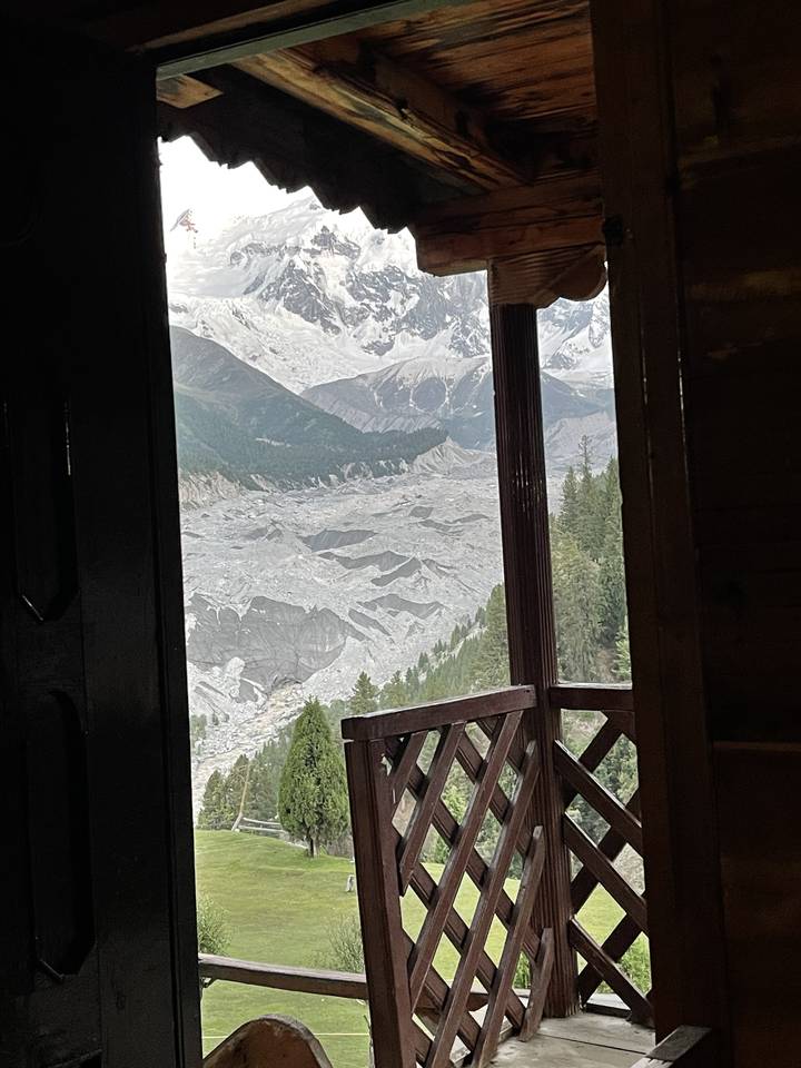 View from a wooden porch overlooking mountains and glaciers.
