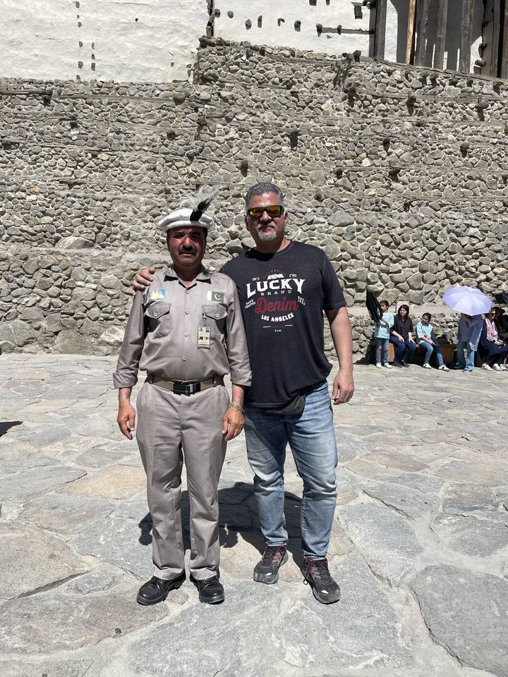 Two men posing in front of a historical stone wall.