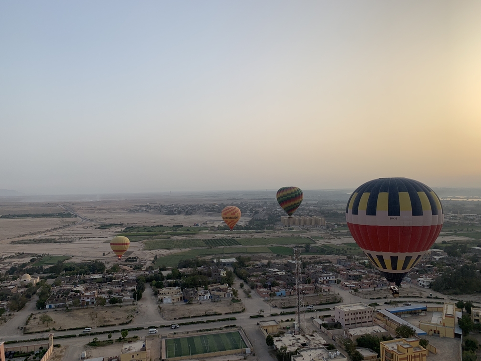Hot air balloons floating over a city at dawn.