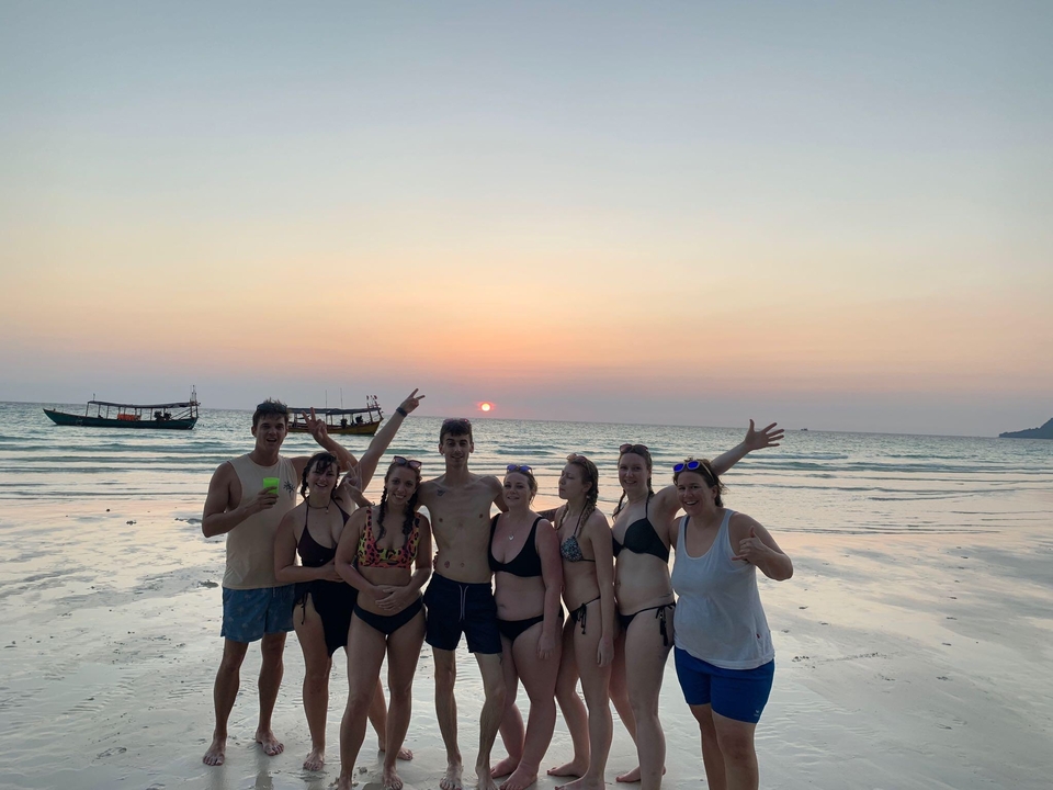 Group of people posing on the beach at sunset.