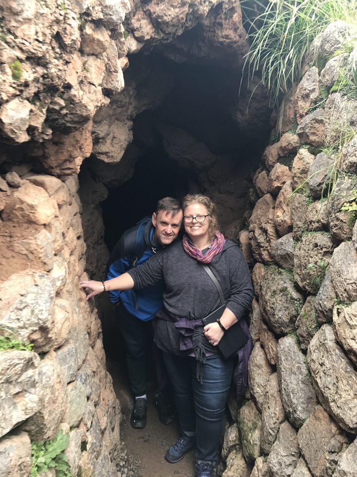 Deux personnes posant à l'entrée d'une formation rocheuse ou d'une grotte.