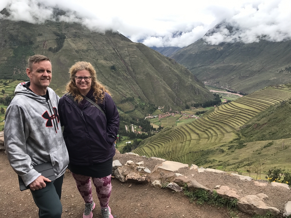 Couple posant avec un arrière-plan de champs en terrasses dans une vallée.