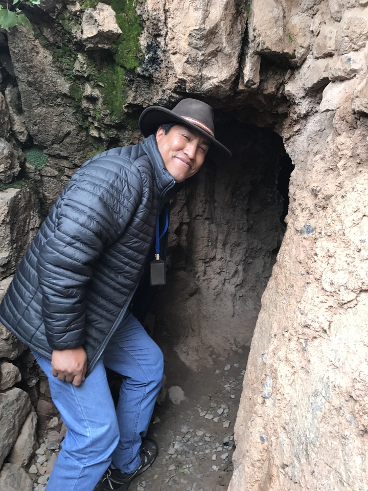 Personne en veste d'hiver posant près d'une entrée rocheuse.