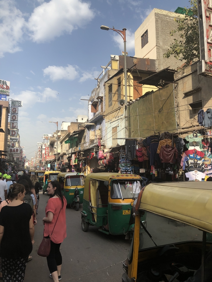 Rue animée avec divers magasins et pousse-pousse motorisés.