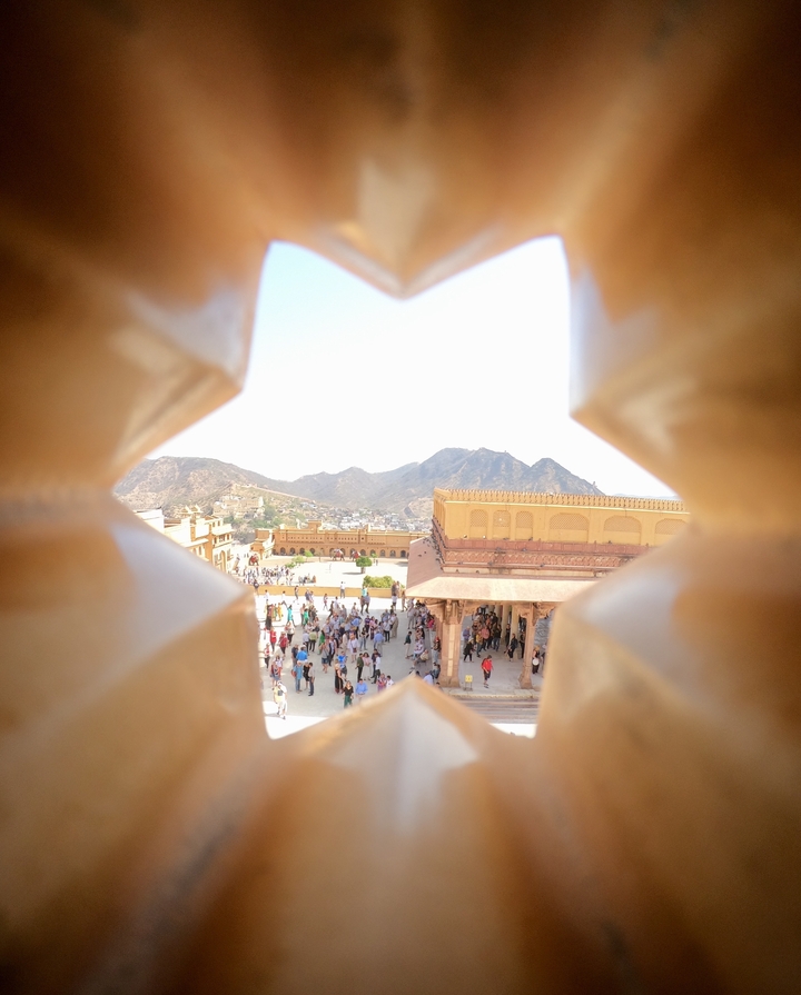 Vue d'une cour de fort avec des visiteurs et un arrière-plan montagneux.