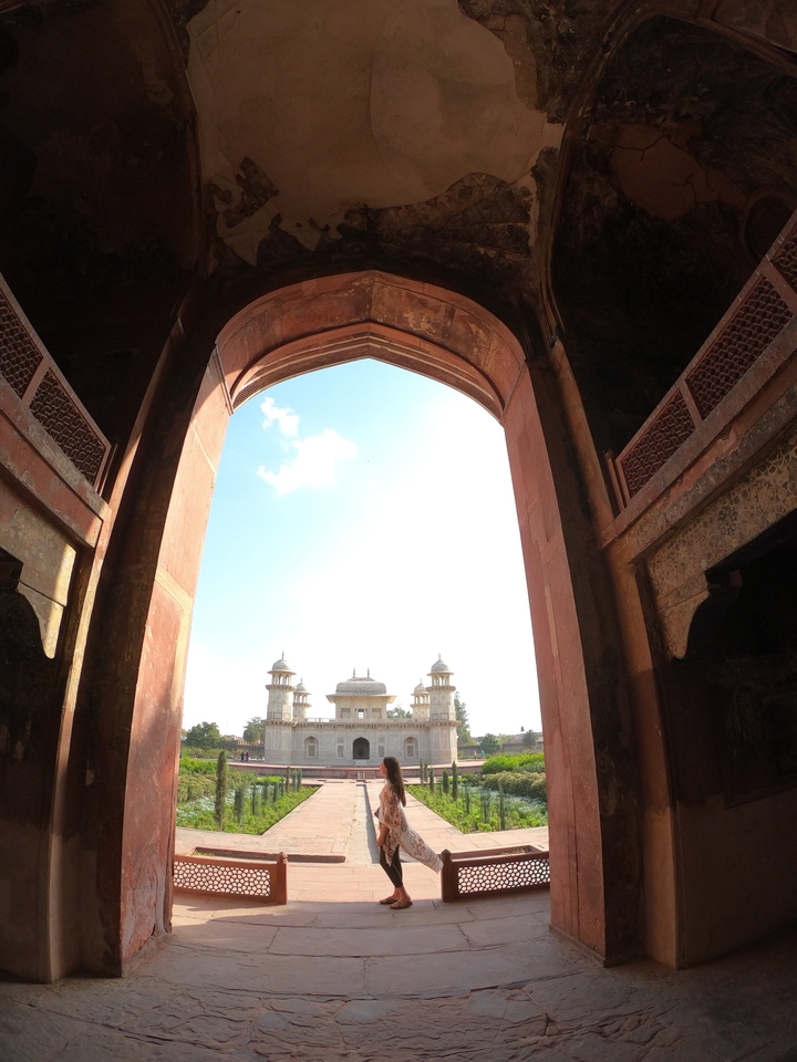 Vue à travers une arcade montrant un bâtiment historique avec un ciel bleu dégagé.