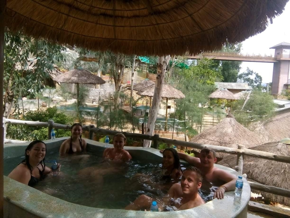 Group of people relaxing in a hot tub with greenery around.