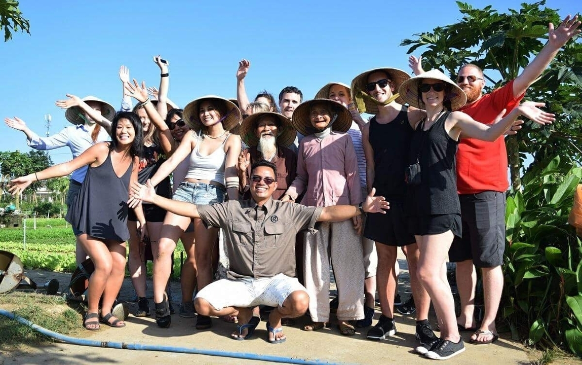 Large group of people outdoors, smiling and posing.